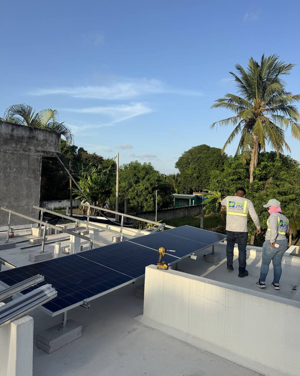 Cuadrilla de ECO JTC instalando paneles solares en una azotea con palmeras